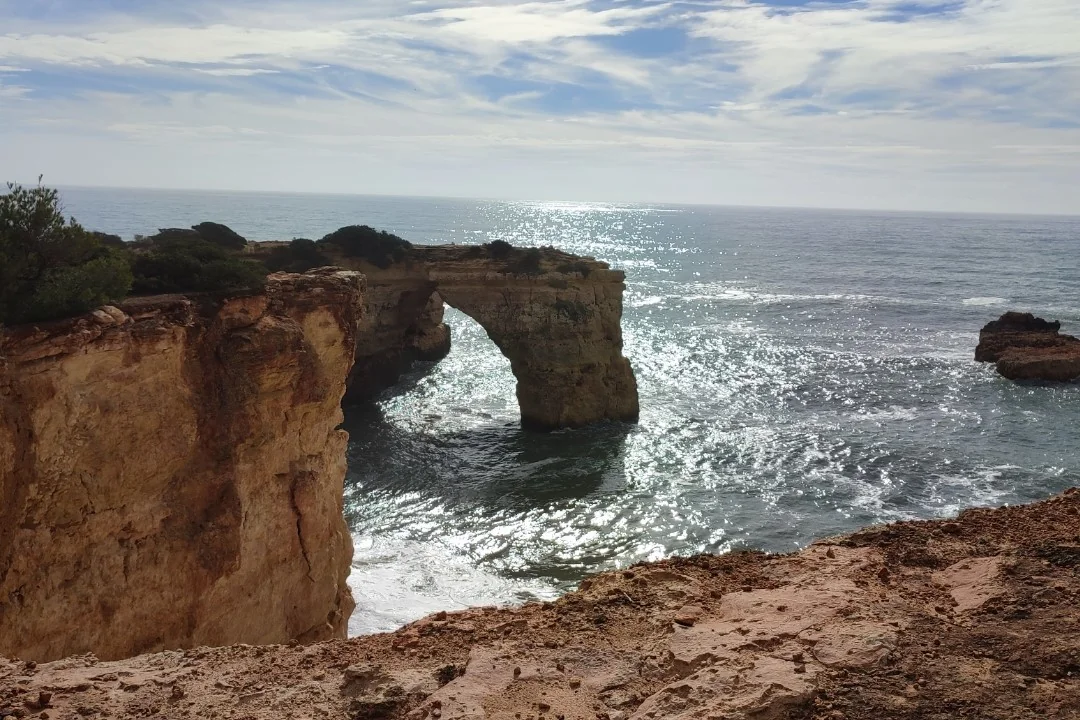 A natural sandstone arch above the foaming sea on the Algarve coast